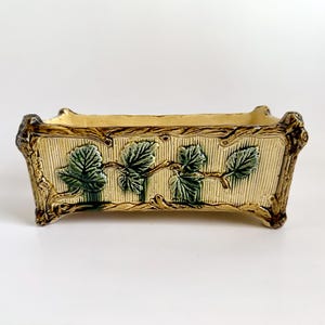 May include: A set of three ceramic mugs with a speckled, cream-colored glaze. Each mug features a different hand-painted design: a blue and green leaf, a yellow flower, and a red berry. The mugs have a simple, modern design.