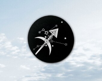 May include: Black circle with a white outline of the Sagittarius zodiac symbol, including an arrow and crescent moon, surrounded by white stars.