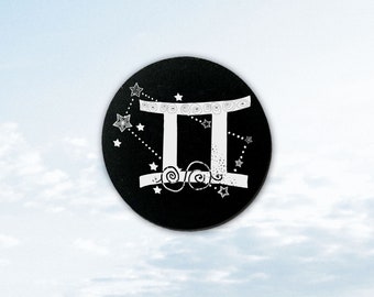 May include: Black circle with a white Gemini zodiac symbol and stars. The symbol is a stylized representation of the Gemini constellation.
