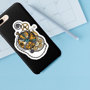 May include: A black phone case with a sticker of a gold and blue clockwork design. The sticker features intricate details and a chain.