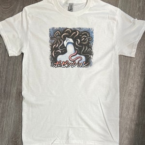Puede incluir: Camiseta blanca con un estampado gr&aacute;fico de una mujer con serpientes como cabello. El texto "ホセダンジョン" est&aacute; impreso debajo de la imagen.