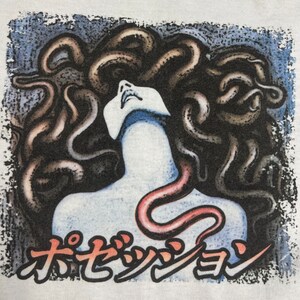 Puede incluir: Una ilustraci&oacute;n en blanco y negro de una mujer con serpientes como cabello. La boca de la mujer est&aacute; abierta y ella est&aacute; mirando hacia arriba. El texto "オセッショ" est&aacute; impreso debajo de la imagen.