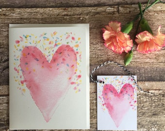 Carte de note aquarelle + étiquette cadeau assortie d'un joli cœur rose et de confettis.