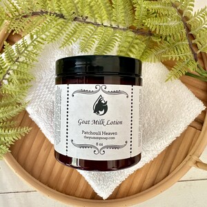 May include: An 8 oz amber plastic jar of Goat Milk Lotion with a black screw-top lid. The white label features a black goat head logo, the text Goat Milk Lotion, Patchouli Heaven, theyummysoap.com, and 8 oz in a decorative border.