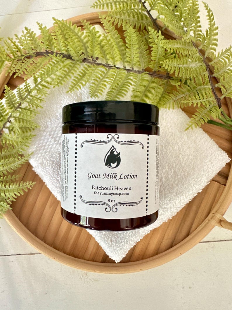 May include: An 8 oz amber plastic jar of Goat Milk Lotion with a black screw-top lid. The white label features a black goat head logo, the text Goat Milk Lotion, Patchouli Heaven, theyummysoap.com, and 8 oz in a decorative border.