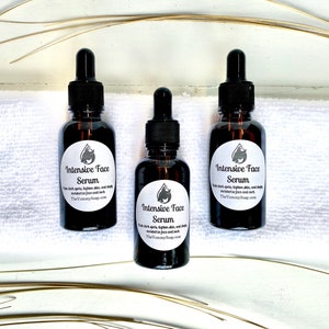 May include: Three brown glass bottles of Intensive Face Serum with black droppers. Each bottle has a white label with a logo and text. The text reads: "Fade dark spots, tighten skin, and deeply moisturize face and neck. TheYummySoap.com."