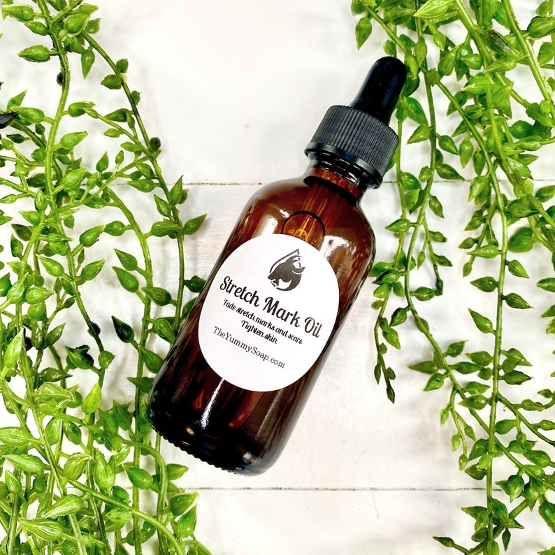 May include: A brown glass bottle with a dropper top filled with stretch mark oil. The bottle has a white label with black text that reads "Stretch Mark Oil" and "Fade stretch marks and scars. Tighten skin. TheYummySoap.com".