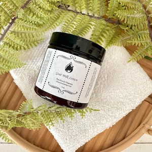 May include: A dark amber glass jar of Goat Milk Lotion with a black screw-top lid. The white label features a black goat icon, the text Goat Milk Lotion, Patchouli Heaven, theyummysoap.com, and 4 oz, framed by decorative black scrollwork.