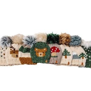 May include: A collection of eight knitted winter hats with different woodland animal and nature-themed designs. Each hat features a pom-pom on top and a variety of colors, including beige, green, brown, red, and white.