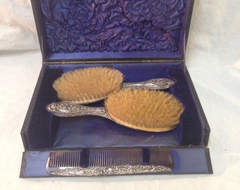 Antique 1910s Sterling Silver 3-piece vanity / dresser set. Includes 2 hair brushes, hair comb, box with purple lining. Marked WJM. English.