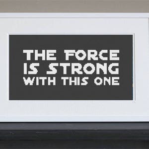 Peut inclure: Impression encadrée blanche avec un fond noir et un texte blanc qui dit "The Force is Strong with This One."