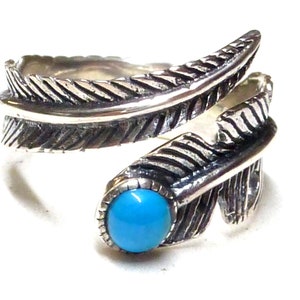 Puede incluir: Un anillo de plata con una piedra turquesa y un diseño de pluma.