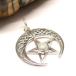 May include: A silver-toned pendant featuring a crescent moon design with Celtic knotwork and a central pentagram. The pentagram holds a small, round, off-white stone. The pendant has a loop for a chain.