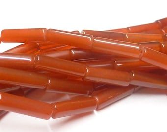 May include: A strand of orange carnelian beads, each bead is a smooth, polished cylinder.