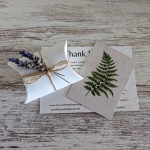 May include: A small white box with a brown twine bow and dried lavender flowers. The box is sitting on a white wooden surface. The text on the card reads "Thank you" and includes the website address www.etsy.com/shop/myjewelk and jewelkatstudio@gmail.com.