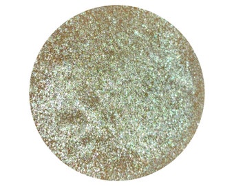 May include: A round, green and gold glitter eyeshadow with a shimmery finish.