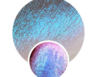 May include: Close-up of a blue and purple iridescent eyeshadow with a shimmery finish.