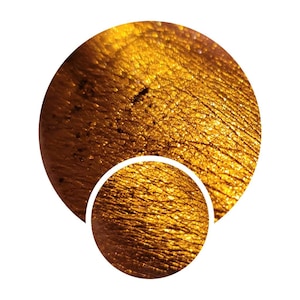 May include: Close-up of a gold eyeshadow with a textured, glittery finish.