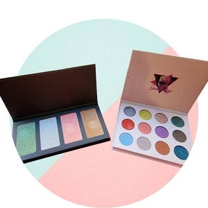 Könnte beinhalten: Zwei offene Make-up-Paletten. Eine Palette hat vier rechteckige Abschnitte mit schimmernden Farbtönen in Grün, Blau, Rosa und Gold. Die andere Palette hat zwölf kreisförmige Lidschatten in verschiedenen Farben, darunter Blau, Rot und Lila. Die Oberseite der zweiten Palette hat ein Logo.