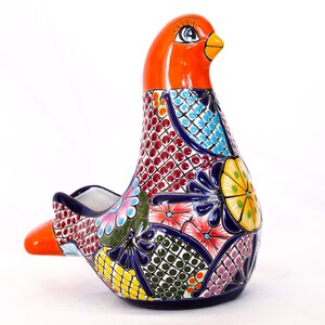 Puede incluir: Un macetero de cerámica en forma de pájaro colorido con un pico naranja brillante y intrincados patrones florales en tonos de azul, verde, amarillo, rosa y rojo.