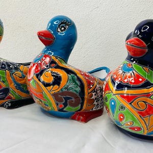 May include: Three ceramic duck planters with colorful, hand-painted designs. The ducks are in various colors, including blue, yellow, and black, and feature intricate patterns.