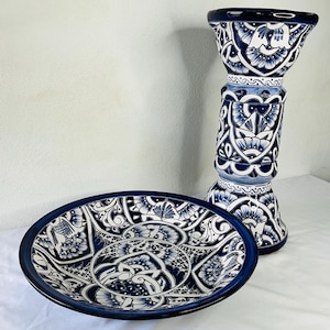 Puede incluir: Un pedestal de cerámica azul y blanco con un plato a juego. El pedestal es alto y tiene una base ancha. El plato es redondo y tiene un diseño decorativo.