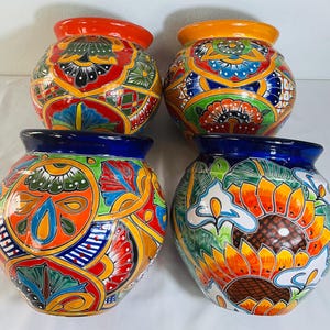 May include: Four round ceramic vases featuring vibrant, hand-painted floral and geometric patterns in shades of orange, yellow, blue, green, and red. Each vase has a wide, rounded body and a smooth, glossy finish with distinct rim colours.