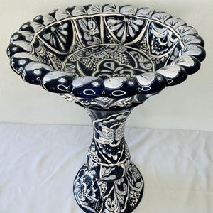 Puede incluir: Un bebedero para pájaros de cerámica negro y blanco con base de pedestal. El bebedero para pájaros está decorado con intrincados patrones florales.