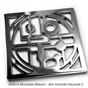 May include: A square, chrome-plated drain cover with a geometric design. The design features a circle with a smaller circle inside, and a series of lines and curves.