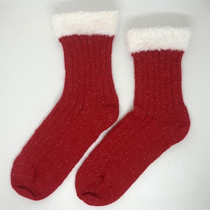 May include: A pair of red knit socks with white fluffy trim at the top. The socks have a ribbed texture and a speckled pattern. The socks are designed for warmth and comfort.