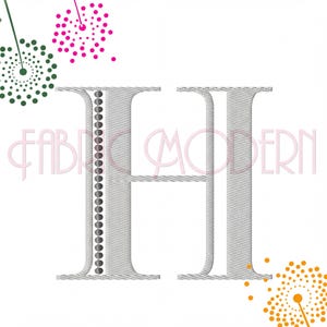 May include: A large, silver-toned embroidered letter H featuring a vertical row of dark grey dots along the left side. The design is surrounded by stylized dandelion-like floral patterns in pink, dark green, and orange. The text FABRIC MODERN is visible.
