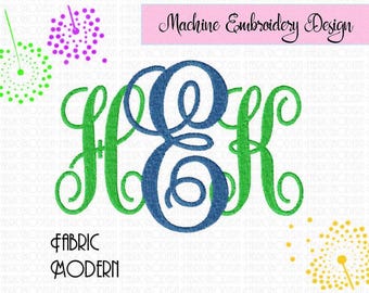 May include: A machine embroidery design featuring a large, blue, cursive monogram letter E centered between two green, cursive monogram letters H and K. The text Machine Embroidery Design appears in a pink box, with FABRIC MODERN below.