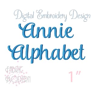 Op de afbeelding: Digitaal borduurontwerp met de naam "Annie" en het woord "Alphabet" in een cursief, lichtblauw lettertype. De tekst is ongeveer 2,5 cm hoog. Het Fabric Modern-logo staat in de linker benedenhoek.