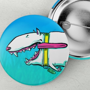 Puede incluir: Dos botones redondos con una ilustración de dibujos animados de un perro blanco con la lengua fuera. El perro tiene un collar amarillo y está sobre un fondo degradado azul y turquesa. Un botón está abierto, mostrando la parte trasera del alfiler.