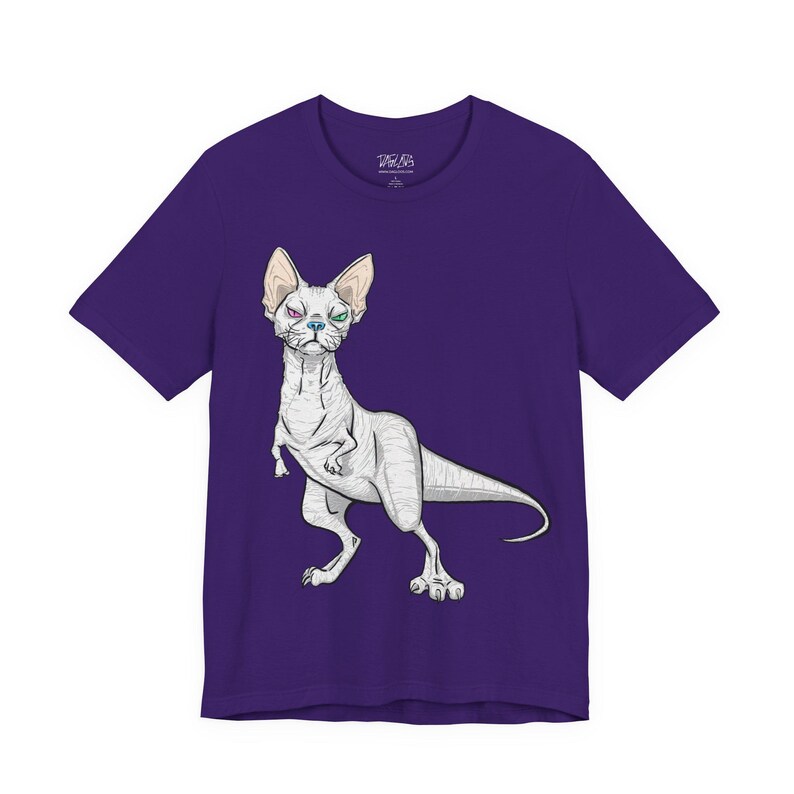 May include: A purple short-sleeved t-shirt featuring a graphic illustration of a hairless cat with a dinosaur-like body, a long tail, and heterochromia with one purple eye and one green eye, centered on the front of the garment.