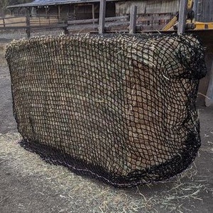 May include: A black hay net filled with hay. The net is made of a strong, durable material and is designed to slow down feeding.