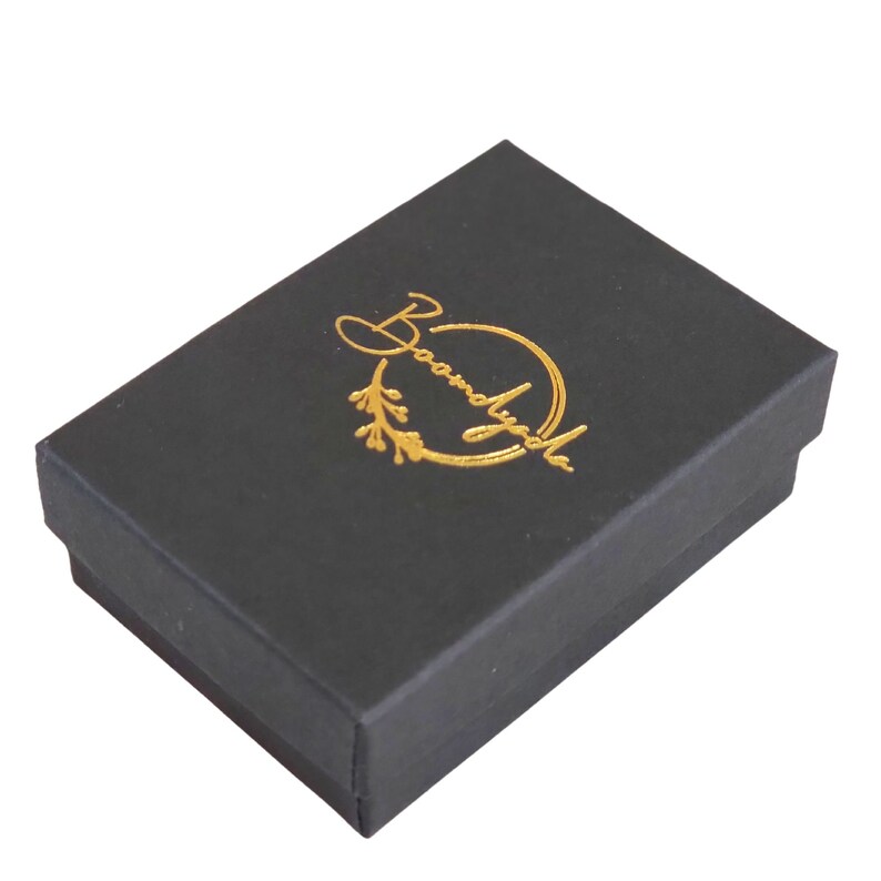 This photo shows that your jewelry will arrive in a custom black matte jewelry box with a gold foil-stamped Boomdyada logo centered on the outside of the lid. This elegant box is perfect for gift-giving! All orders ship the next business day.