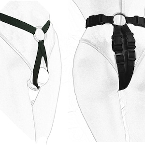 May include: Two black harnesses with metal rings and buckles. One harness is a simple design with a single ring, while the other has a more complex design with multiple buckles and rings.