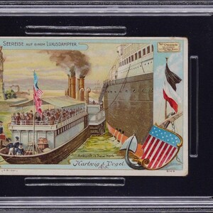 May include: A 1909 Hartwig & Vogel trading card titled Seereise auf einem Luxusdampfer, encased in a PSA slab. The illustration depicts a steamship arriving in New York with the Statue of Liberty, an American flag, and a shield in the foreground.