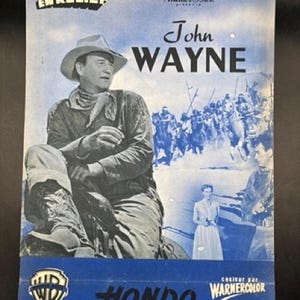 May include: Vintage movie poster for "Hondo" starring John Wayne. The poster features a blue and white color scheme with an image of Wayne in a cowboy hat. Text includes "Warner Bros." and "Hondo L'Homme du Desert".