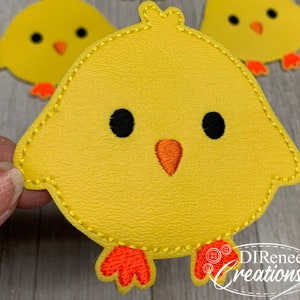 May include: Close-up of three yellow chick-shaped appliques. Each chick has black eyes, an orange beak, and orange feet. The appliques are stitched with yellow thread. The bottom right corner of the image has the text "DIRenee Creations".