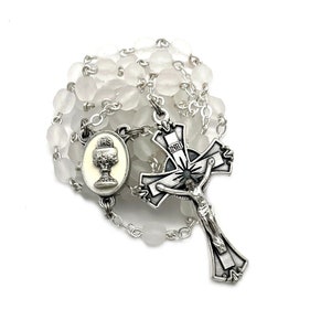 May include: White glass bead rosary with a silver crucifix and a silver chalice pendant.