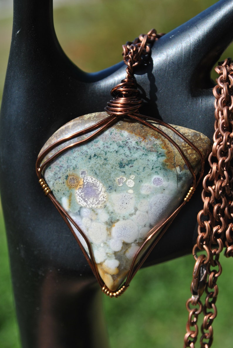 May include: A copper wire wrapped pendant featuring a green, white and brown agate stone with a copper chain.