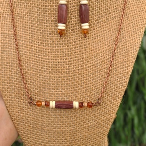 May include: A copper chain necklace with a brown wooden bead and amber colored beads. Matching earrings with brown wooden beads and amber colored beads.