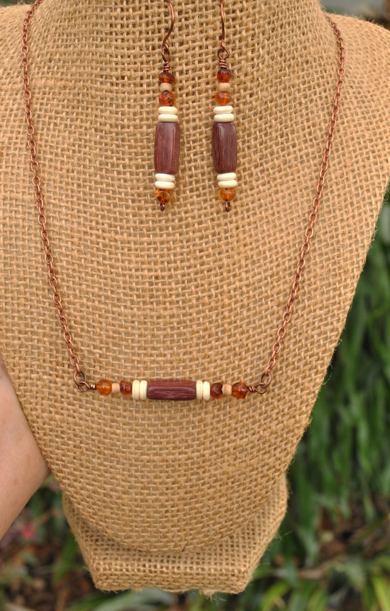 May include: A copper chain necklace with a brown wooden bead and amber colored beads. Matching earrings with brown wooden beads and amber colored beads.