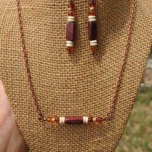 May include: A copper chain necklace with a wooden bead and amber-colored glass beads. Matching earrings with wooden beads and amber-colored glass beads.