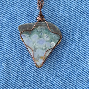 May include: A copper chain necklace with a pendant featuring a green, blue, and white agate stone wrapped in copper wire.