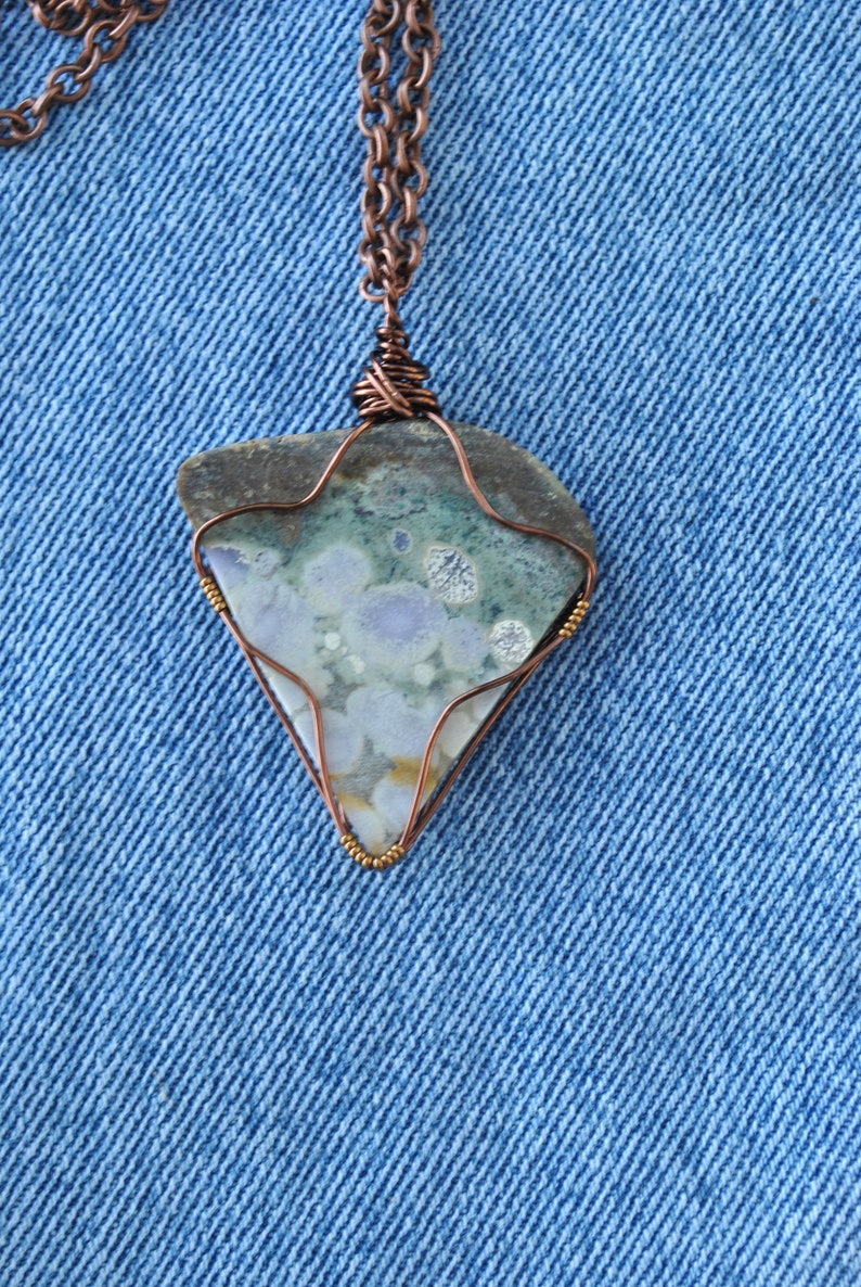 May include: A copper chain necklace with a pendant featuring a green, blue, and white agate stone wrapped in copper wire.