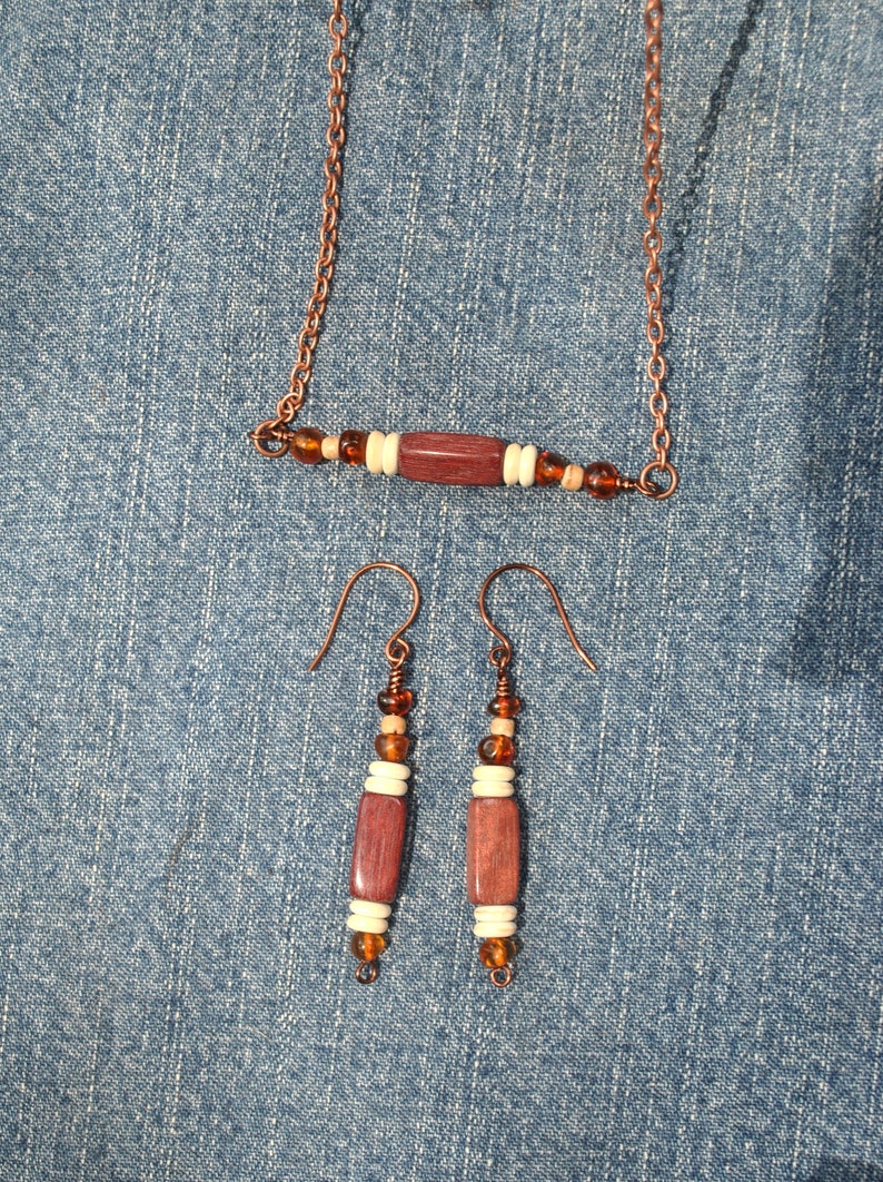 May include: A copper chain necklace with a wooden bead and amber beads. Matching earrings with wooden beads and amber beads.