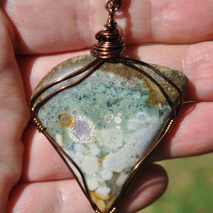 May include: A copper wire wrapped pendant featuring a green, white and brown agate stone with a copper chain.